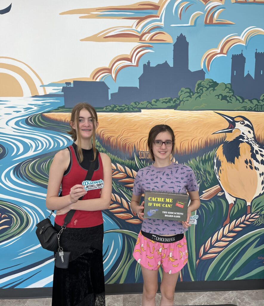 SJ and Dublynn Franks, pre-teen girls, hold up their prizes of a patch and geocaching board game for winning the first Mitchell County GeoTrail!